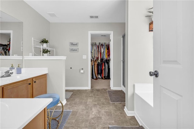 full bath featuring vanity, visible vents, a shower stall, a walk in closet, and a bath