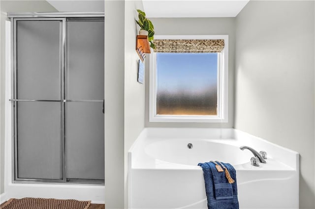 bathroom featuring a garden tub and a shower stall