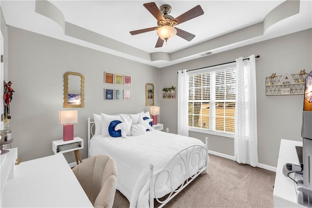 carpeted bedroom featuring baseboards, a raised ceiling, visible vents, and a ceiling fan