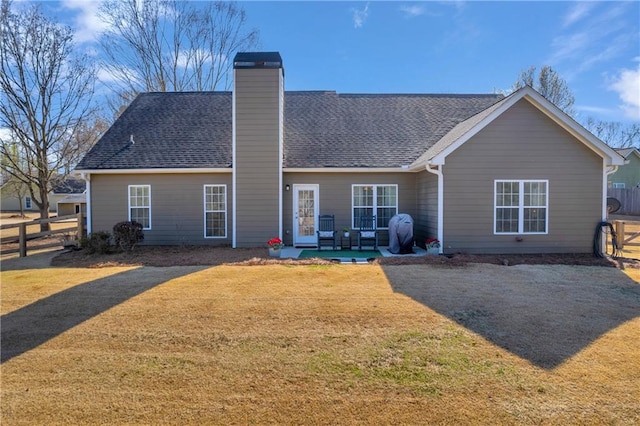 rear view of property with a yard, fence, and a chimney