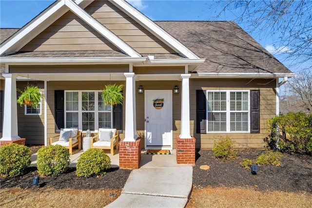 entrance to property with a porch and a shingled roof