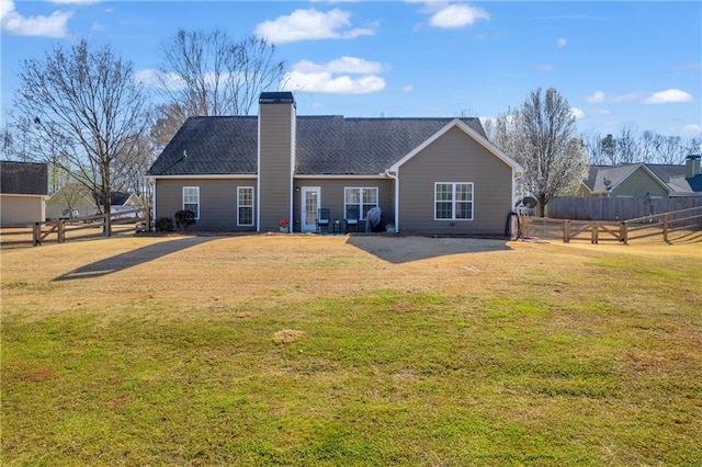 rear view of property featuring a lawn, a chimney, and fence