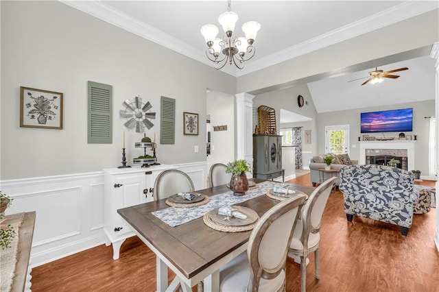 dining area with a high end fireplace, ceiling fan with notable chandelier, crown molding, and wood finished floors