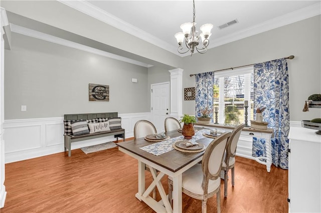 dining room with crown molding, light wood-style floors, visible vents, and a chandelier