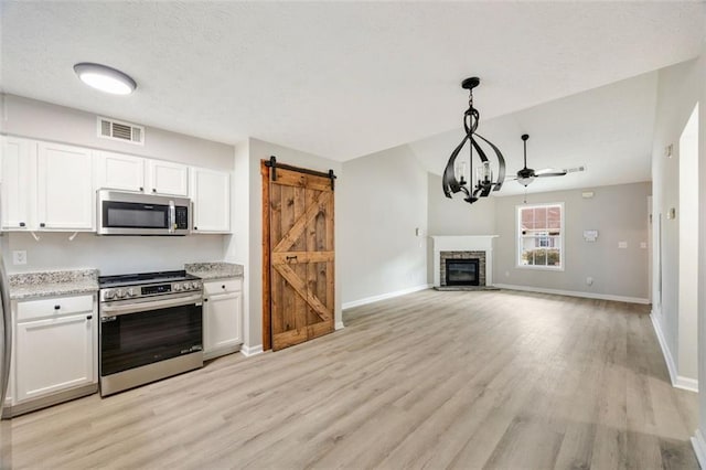 kitchen featuring white cabinetry, pendant lighting, a barn door, and appliances with stainless steel finishes