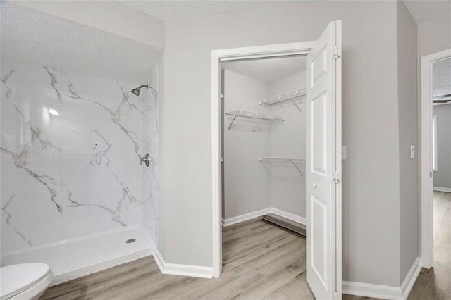 bathroom with toilet, hardwood / wood-style floors, a textured ceiling, and walk in shower