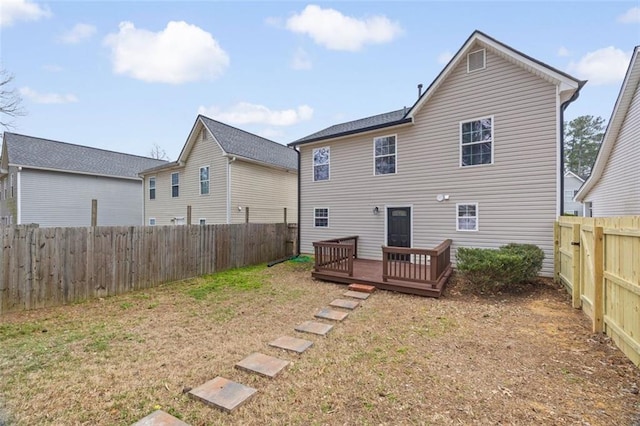 rear view of property featuring a wooden deck and a lawn