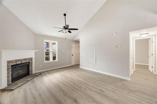 unfurnished living room featuring a stone fireplace, high vaulted ceiling, ceiling fan, and light hardwood / wood-style flooring