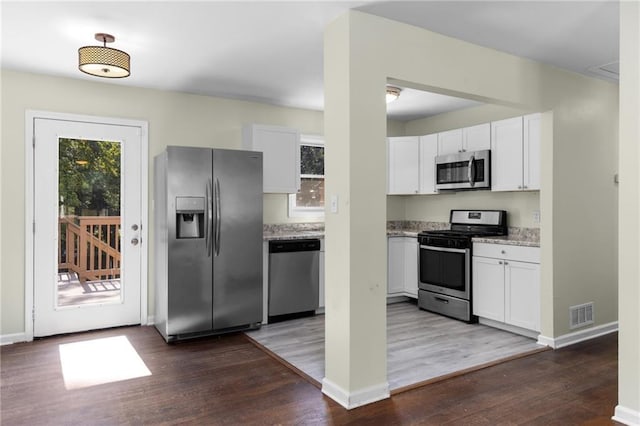 kitchen with visible vents, appliances with stainless steel finishes, dark wood-type flooring, and white cabinetry