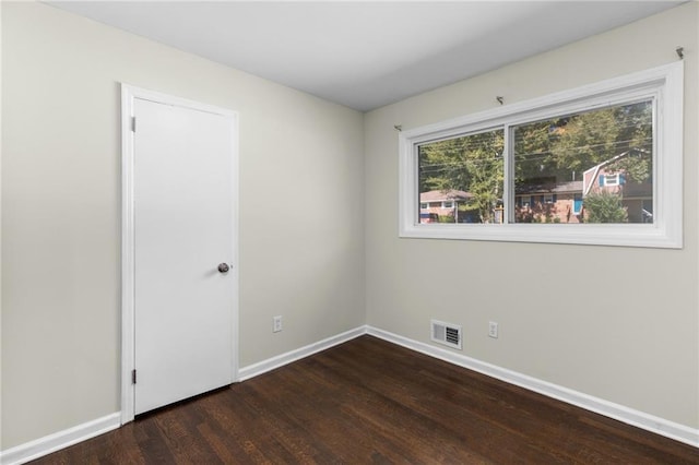 spare room with visible vents, dark wood finished floors, and baseboards