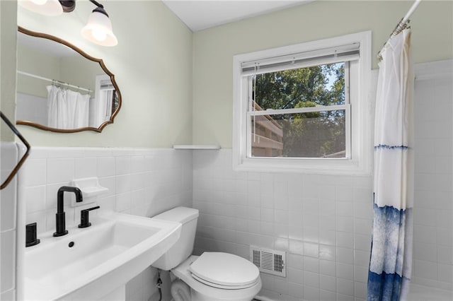 full bathroom with visible vents, wainscoting, toilet, a sink, and tile walls