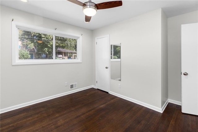 unfurnished bedroom featuring a ceiling fan, dark wood-style flooring, visible vents, and baseboards