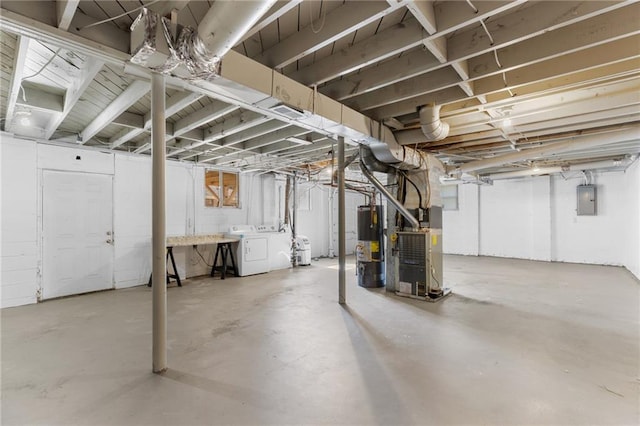 unfinished basement with heating unit, water heater, electric panel, and washer and dryer