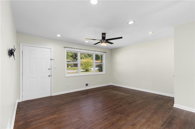 empty room with dark wood-style flooring, visible vents, and baseboards