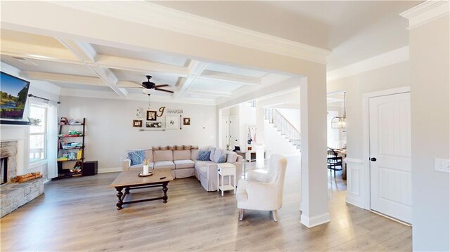 living area with light wood-style floors, coffered ceiling, beamed ceiling, and a stone fireplace