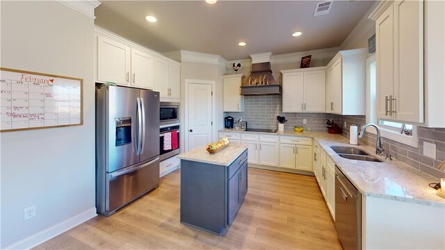 kitchen featuring custom exhaust hood, visible vents, appliances with stainless steel finishes, white cabinets, and a sink