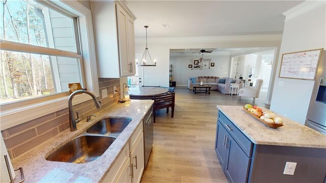 kitchen with blue cabinetry, backsplash, ornamental molding, a sink, and light wood-type flooring