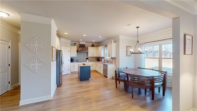 kitchen featuring stainless steel appliances, ornamental molding, backsplash, and light wood finished floors