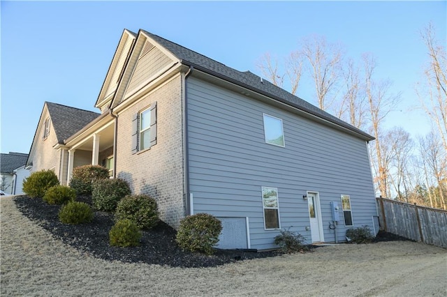 rear view of property with fence and brick siding