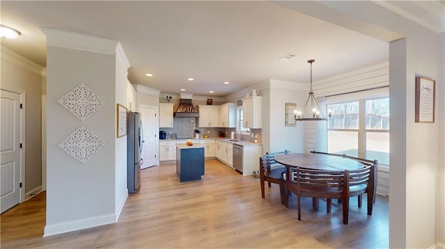 kitchen with white cabinetry, decorative light fixtures, a center island, stainless steel appliances, and decorative backsplash