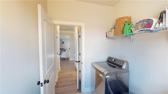 washroom featuring laundry area, washer / clothes dryer, light wood-style flooring, and baseboards