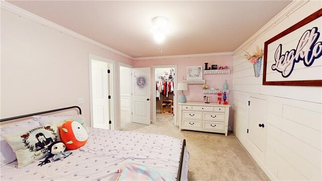 bedroom with a closet, a walk in closet, crown molding, and light colored carpet