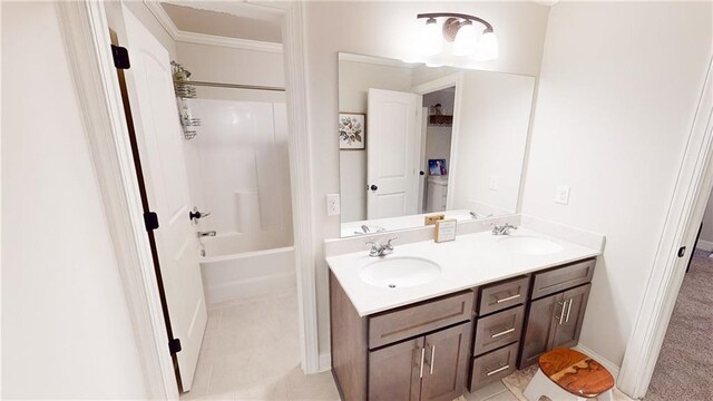 full bathroom with double vanity, shower / bathing tub combination, a sink, and baseboards