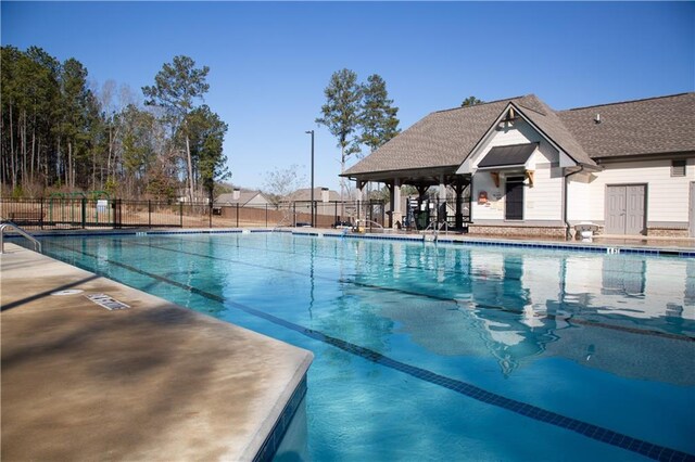 community pool featuring fence and a patio