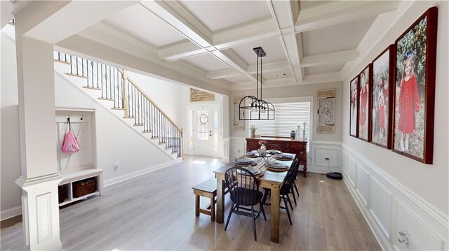 dining room with a decorative wall, coffered ceiling, stairway, light wood finished floors, and beamed ceiling