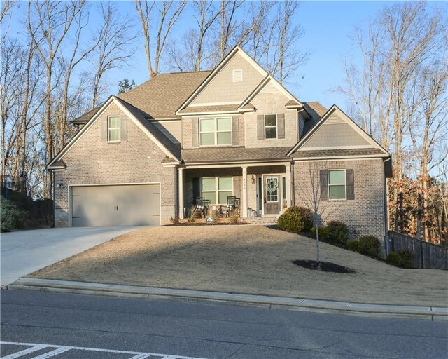 craftsman house with driveway, a porch, an attached garage, and brick siding