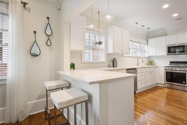 101 Terrace Dr, Atlanta, GA 30305 - kitchen with stainless steel appliances, ornamental molding, light wood finished floors, backsplash, and a kitchen bar