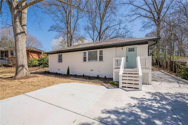 view of front of house with a patio area, brick siding, and crawl space