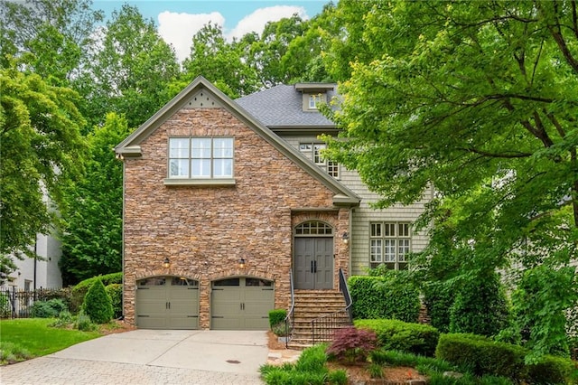 view of front facade featuring stone siding, an attached garage, concrete driveway, and fence