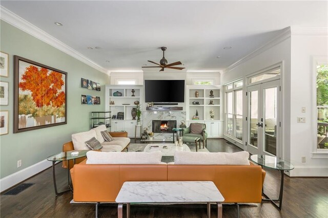 living room featuring ceiling fan, baseboards, ornamental molding, a fireplace, and dark wood-style floors