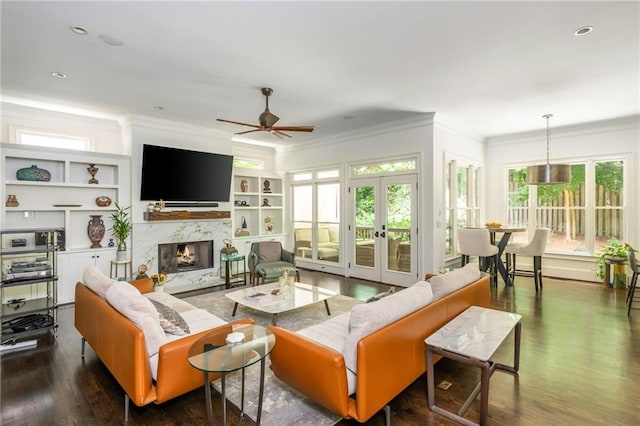 living area with ceiling fan, ornamental molding, a high end fireplace, dark wood-style flooring, and built in features
