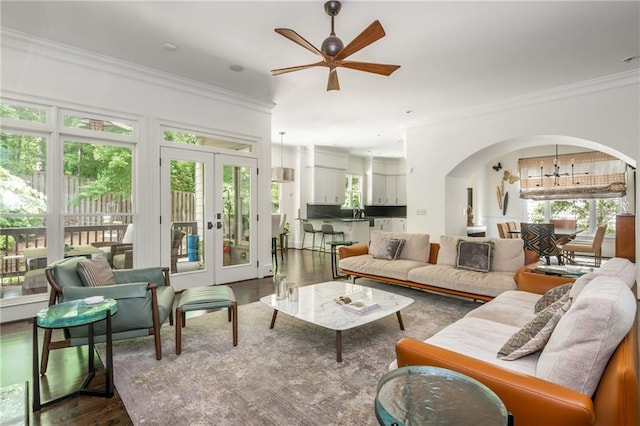 living area featuring dark wood-style floors, ceiling fan, ornamental molding, arched walkways, and french doors
