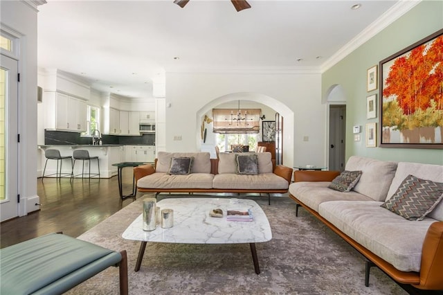 living area featuring arched walkways, ornamental molding, a ceiling fan, dark wood-type flooring, and recessed lighting