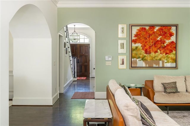 entrance foyer featuring arched walkways, a chandelier, ornamental molding, dark wood-style floors, and baseboards