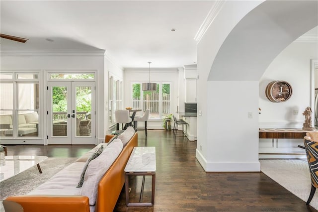 living room with arched walkways, crown molding, wood finished floors, baseboards, and french doors