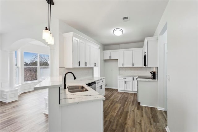 kitchen featuring pendant lighting, white cabinetry, a sink, light stone countertops, and a peninsula