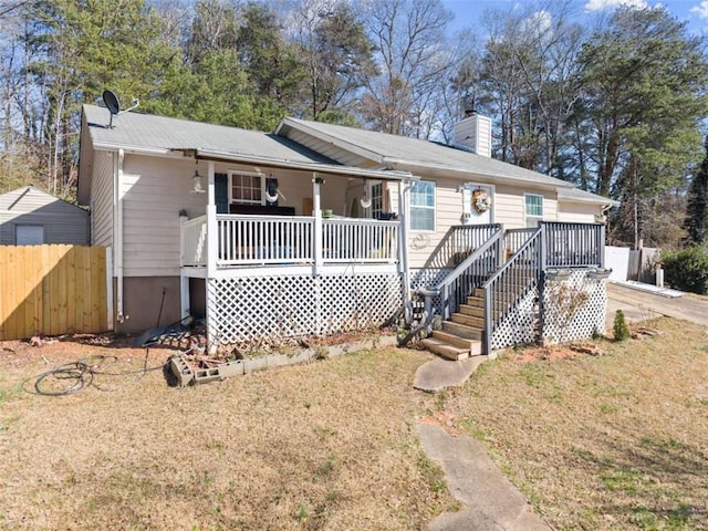 ranch-style home featuring a chimney, covered porch, fence, a front lawn, and stairs