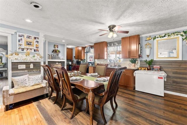 dining space featuring dark wood-style floors, ornamental molding, a textured ceiling, and a ceiling fan