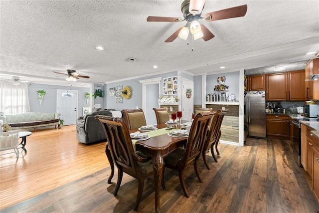 dining area featuring a textured ceiling, wood finished floors, a ceiling fan, and crown molding