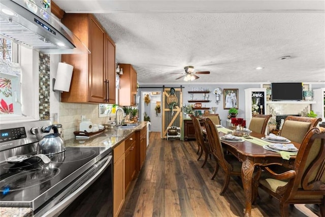 kitchen with range hood, electric stove, brown cabinets, a sink, and light stone countertops