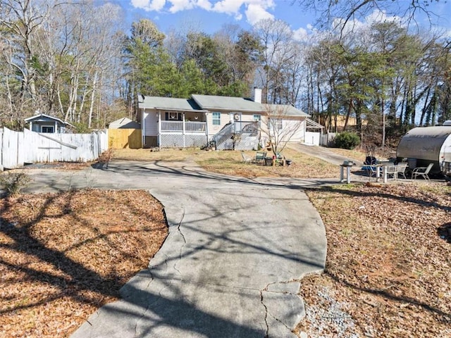 ranch-style home with covered porch, fence, and a chimney