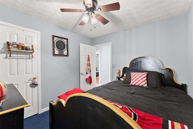 bedroom featuring a textured ceiling, dark colored carpet, and ceiling fan