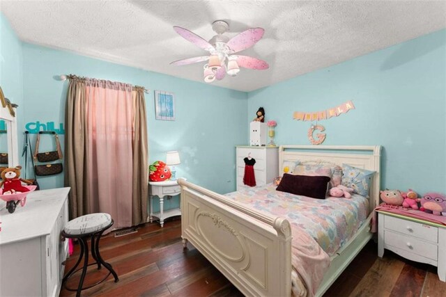 bedroom with a textured ceiling, a ceiling fan, and dark wood-type flooring