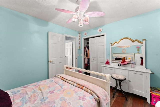 bedroom with dark wood-style floors, a closet, ceiling fan, and a textured ceiling