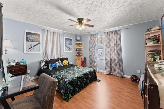 bedroom with light wood-style flooring, baseboards, ceiling fan, and a textured ceiling