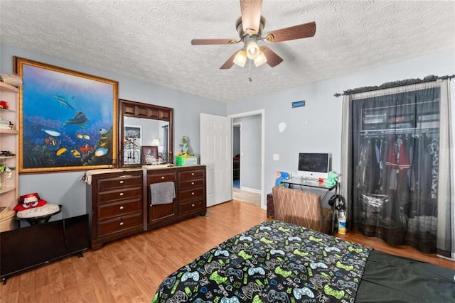 bedroom featuring a textured ceiling, light wood-type flooring, and a ceiling fan